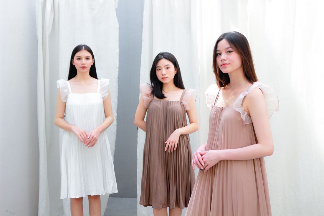 Three models wearing softly pleated dresses